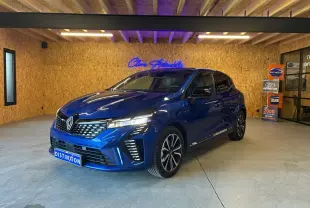Renault Clio V E-TECH 145 TECHNO bleu iron vue 3/4 avant en intérieur avec éclairage LED et jantes bi-ton.