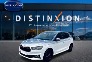 SKODA FABIA blanche vue en 3/4 avant droit, avec jantes noires et calandre distinctive devant un showroom Distinxion.