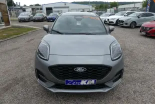Vue avant d'un Ford Puma gris métallisé avec calandre noire et plaque "Zéro KM" sur un parking extérieur.
