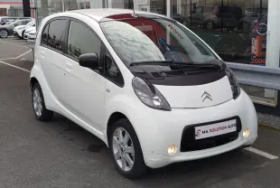 Citroën C-Zero blanc Antarctique vue 3/4 avant droit, avec phares antibrouillard allumés et rétroviseurs noirs.