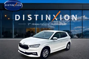 Vue 3/4 avant droite d'une Skoda Fabia blanche garée devant une vitrine avec logo Distinxion.