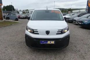 Vue avant d'un Peugeot Partner XL blanc avec calandre noire et phares allumés sur un parking.