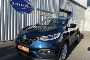 Renault Kadjar bleu 2019 en 3/4 avant droit, avec calandre noire et feux LED, stationné devant un bâtiment gris.