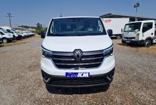 Renault Trafic Fourgon blanc en 3/4 avant droit, avec calandre noire et phares LED distinctifs, sur parking extérieur.