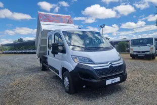 Citroën Jumper blanc en 3/4 avant droit avec benne relevée et ridelles grillagées rouges visibles.