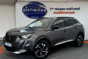 Peugeot 2008 gris foncé vue en 3/4 avant droit, avec jantes noires et toit panoramique visible en intérieur showroom.