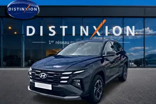 Hyundai Tucson 1.6 t-gdi 239 hybride gris ecotronique vu en 3/4 avant devant un bâtiment vitré Distinxion.