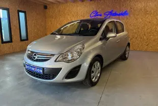 Opel Corsa gris clair vue 3/4 avant droit dans un showroom avec mur en bois et enseigne lumineuse bleue.