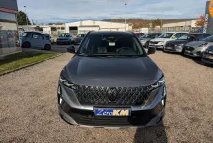 Vue avant d'un Renault Austral gris métallisé avec calandre noire et plaque Zéro KM visible en concession.