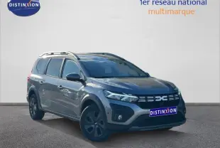 Dacia Jogger 2025 gris schiste métallisé, vue 3/4 avant droit, avec barres de toit et jantes noires distinctives.