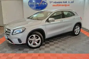Mercedes GLA 200 d gris clair vue 3/4 avant droit en intérieur avec jantes alliage et phares LED allumés.