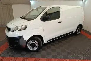 Vue 3/4 avant droit du Peugeot Expert Fourgon blanc avec pare-chocs noirs et jantes acier en intérieur fermé.