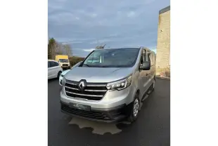 Renault Trafic Fourgon gris clair vu en 3/4 avant droit sur parking avec calandre noire et phares LED.