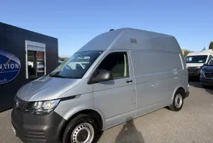 Vue 3/4 avant droit d’un Volkswagen Transporter gris clair version 2.0 TDi 110 L2H1 Business avec jantes acier.