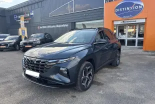 Hyundai Tucson Teal Blue Métal en 3/4 avant droit, calandre chromée et jantes alliage visibles devant un concessionnaire.