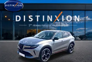 Vue 3/4 avant droite d'une Alfa Romeo Junior 1.2 hybride gris/noir avec jantes alliage et toit noir devant un showroom Distinxion.