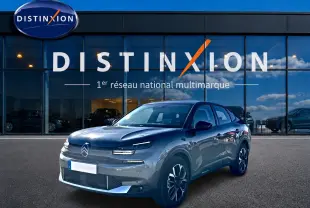 Citroën C4 X gris mercure en 3/4 avant droit devant une vitrine avec logo Distinxion.