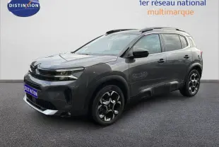 Citroën C5 Aircross Hybrid gris platinium en 3/4 avant droit avec jantes bicolores et barres de toit noires.