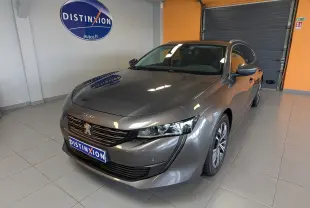 Peugeot 508 SW gris en 3/4 avant droit dans un showroom avec logo Distinxion en arrière-plan.