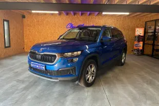 SUV SKODA KODIAQ bleu 2023 en 3/4 avant droit, avec calandre noire et jantes argentées, dans un showroom intérieur.