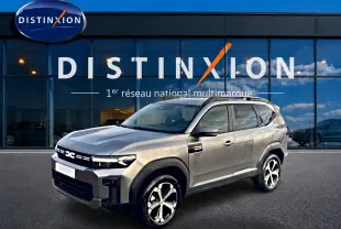 Vue 3/4 avant droit du Dacia Bigster gris schiste avec jantes alliage diamantées, barres de toit et calandre distinctive.