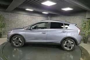 Vue de profil côté gauche d’un Hyundai Bayon gris métallisé avec jantes alliage 17 pouces dans un showroom.