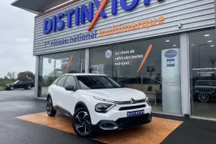 Citroën C4 blanc vue 3/4 avant droit, avec jantes noires et toit noir devant un showroom Distinxion.