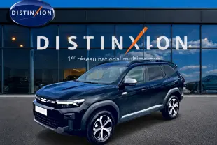SUV Dacia Bigster noir en 3/4 avant droit, avec jantes alliage diamantées et barres de toit visibles devant un showroom.