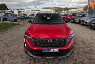 Vue avant d'un Renault Austral rouge métallisé avec calandre noire et feux LED distinctifs sur un parking.