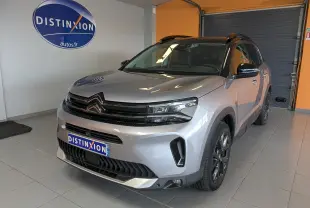 Vue 3/4 avant droite d'un Citroën C5 Aircross gris Artens avec toit noir, en intérieur showroom.