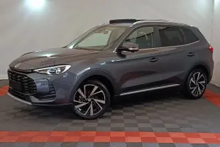 MG Motor ZS gris foncé en vue 3/4 avant droit, avec jantes alliage noires et toit ouvrant panoramique.