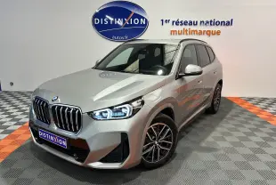 BMW X1 sDrive20d M Sport 2024 en gris Spacesilber, vue 3/4 avant avec phares LED allumés dans un showroom