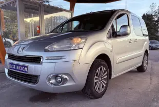 Vue 3/4 avant droit d'un Peugeot Partner Tepee gris 2014 avec phares allumés et jantes spécifiques Family.