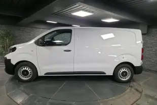 Opel Vivaro blanc vu de profil côté gauche, fourgon utilitaire avec roues tôles et poignées noires.
