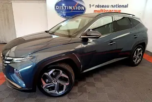 Vue 3/4 avant droit du Hyundai Tucson bleu 2023 avec jantes alliage et toit noir dans un showroom.