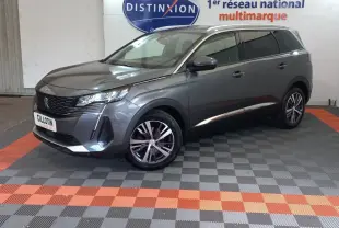 Peugeot 5008 gris foncé en 3/4 avant droit, avec jantes alliage et toit noir brillant en intérieur showroom.