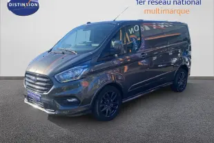 Ford Transit Custom Fourgon gris magnetic en 3/4 avant droit, avec jantes noires et calandre chromée visible.
