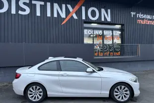 BMW Série 2 blanche vue de profil côté gauche, coupé 2 portes avec jantes alliage et toit ouvrant.