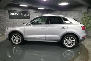 Audi Q3 gris métallisé vue de profil côté gauche dans un showroom avec jantes en alliage cinq branches.
