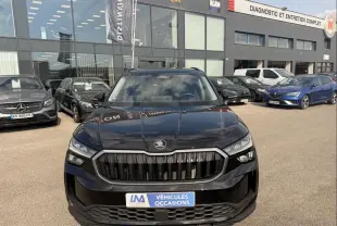 Vue avant d'un Skoda Kodiaq noir 2024 avec calandre verticale distinctive, stationné devant un garage multimarque.