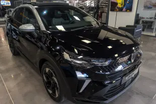 Renault Captur E-Tech hybride 2026 noir avec toit gris, vue 3/4 avant droit en intérieur showroom.