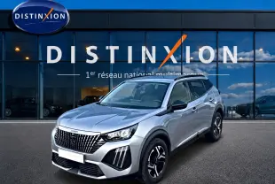 Peugeot 2008 gris artense en 3/4 avant droit devant une vitrine Distinxion, avec jantes alu et feux LED distinctifs.
