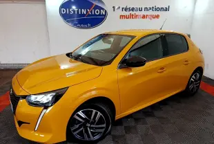 Peugeot 208 jaune vue 3/4 avant droit, feux LED distinctifs et jantes alliage noires en intérieur showroom.