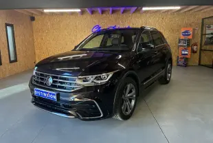 Volkswagen Tiguan noir en 3/4 avant droit dans un showroom avec jantes alu et calandre chromée.