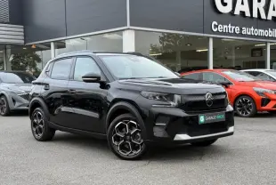 Citroën C3 électrique noir Perla Nera en 3/4 avant droit, avec jantes spécifiques et calandre moderne, devant un garage.
