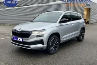 Vue 3/4 avant droite d'un Skoda Karoq gris argent métallisé avec calandre noire et jantes foncées.