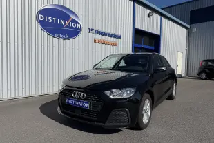 Audi A1 Sportback noir mythic vue en 3/4 avant droit devant un bâtiment industriel avec logo Distinxion.