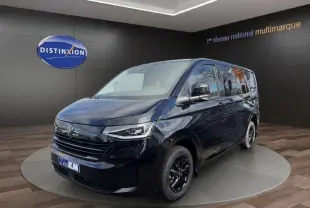 Vue 3/4 avant droit d'un Volkswagen Transporter noir 2026 avec jantes noires et phares LED dans un showroom.