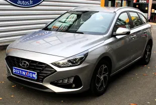 Hyundai i30 SW 2024 argent vue 3/4 avant droit avec calandre noire et jantes alliage bicolores.