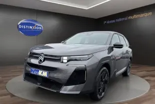 Vue 3/4 avant d'une Citroën C5 hybride gris foncé avec phares LED et jantes noires dans un showroom.